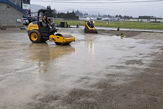 Machinery grading and compacting a parking lot